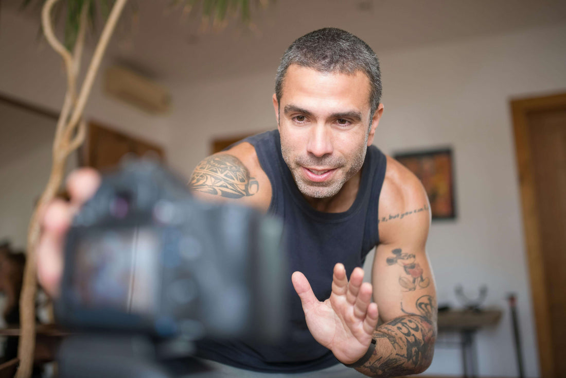 Man with tattoos holding a camera in an indoor setting