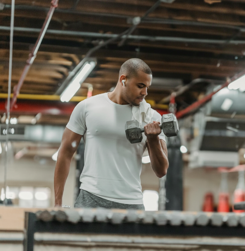 Man exercising with dumbbells in a gym setting