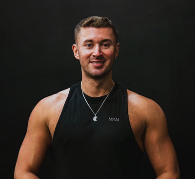 Man wearing a black tank top with a brand logo on a dark background