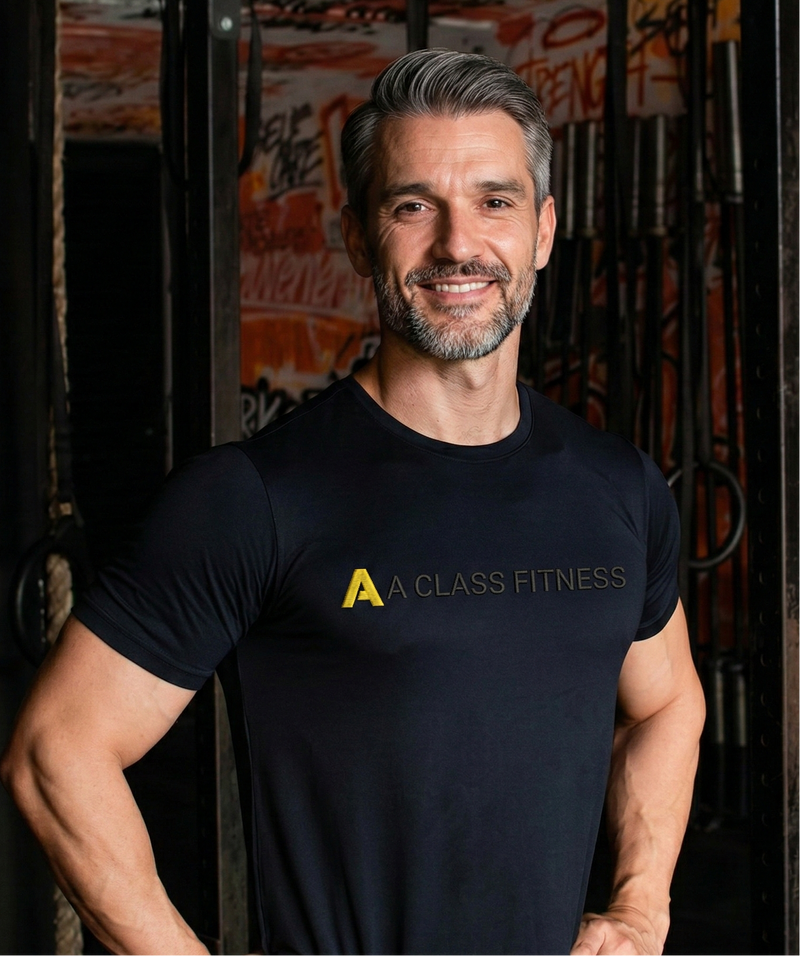 Man wearing a black 'A Class Fitness' t-shirt in a gym setting