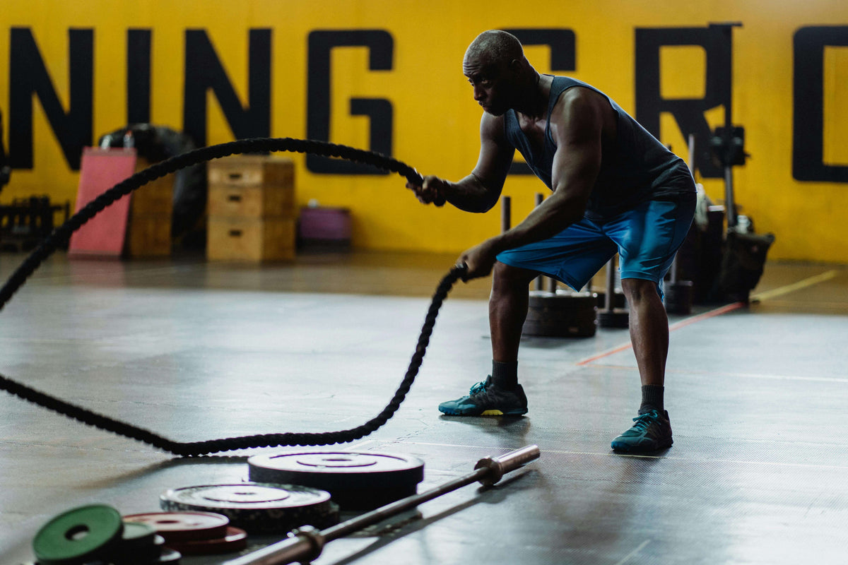 Person using battle ropes in a gym setting with 'Gym' text on the wall.