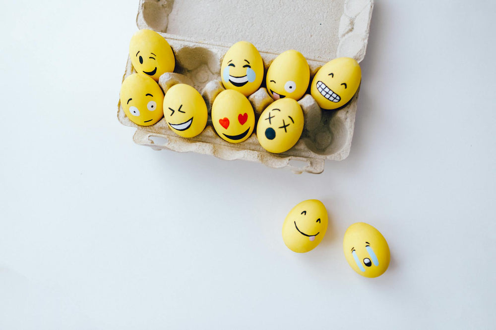 Carton of eggs with emoji faces on a white background