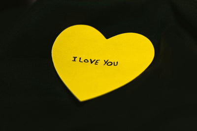 Yellow heart-shaped card with 'I LOVE YOU' text on a black background